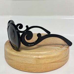 Black round Prada sunglassess with ornate arms.